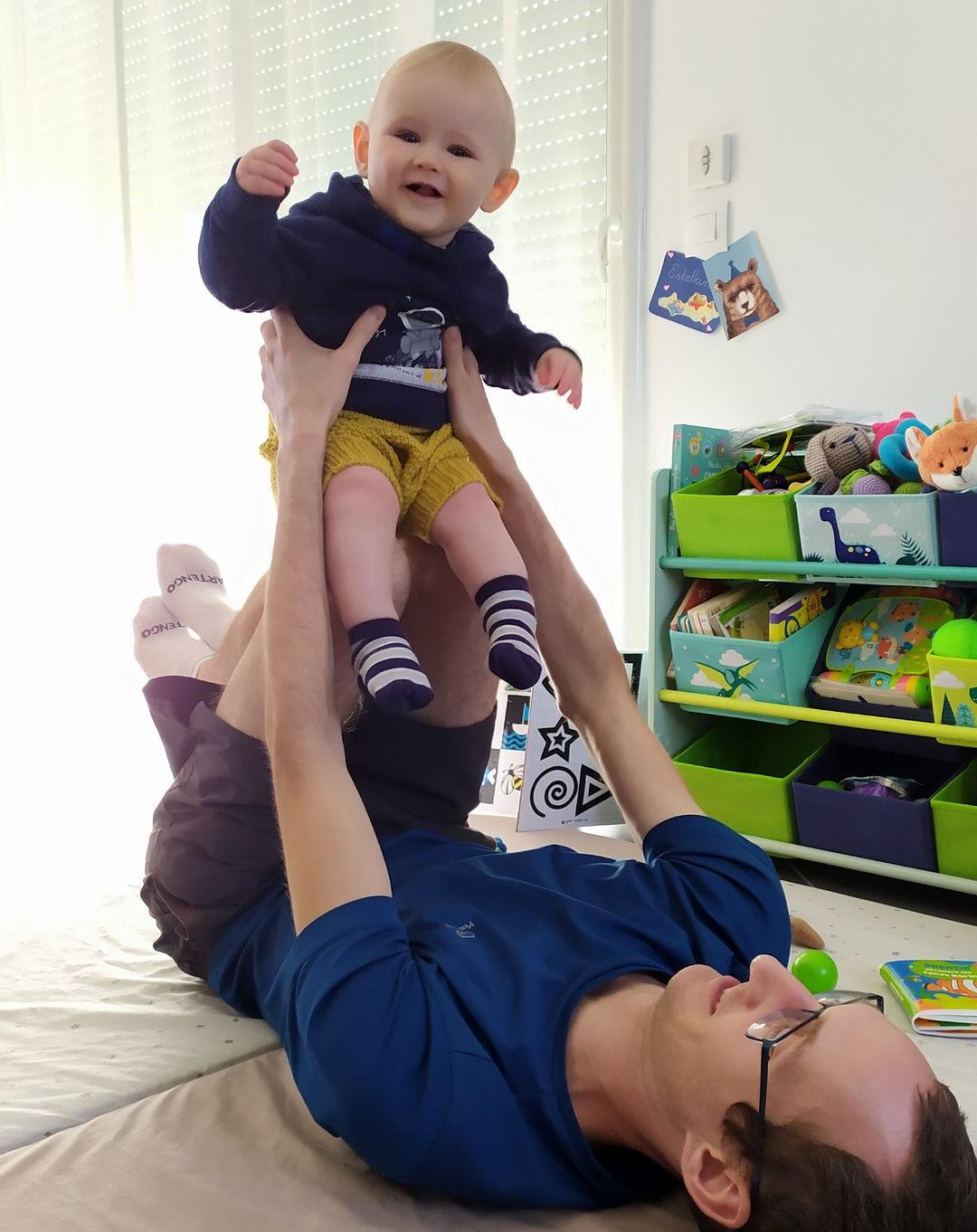 bébé en train de faire de l'accro yoga sur les genoux d'un adulte