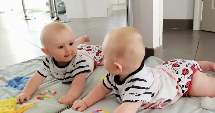 bébé en couches lavable qui se regarde dans la glace en tirant la langue