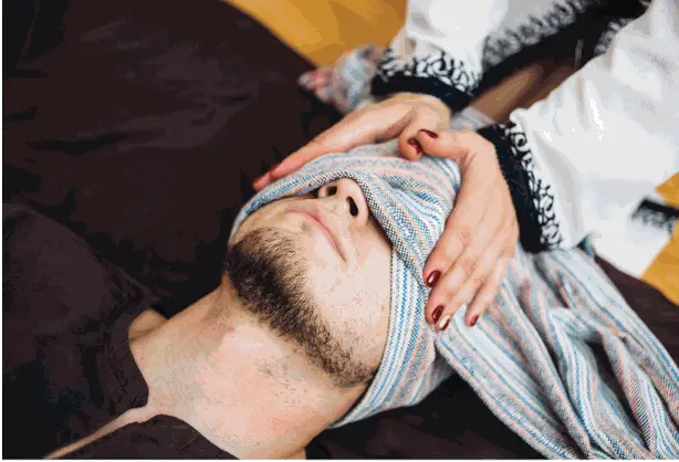 un homme avec le visage recouvert par un rebozo en pleine séance de relaxation