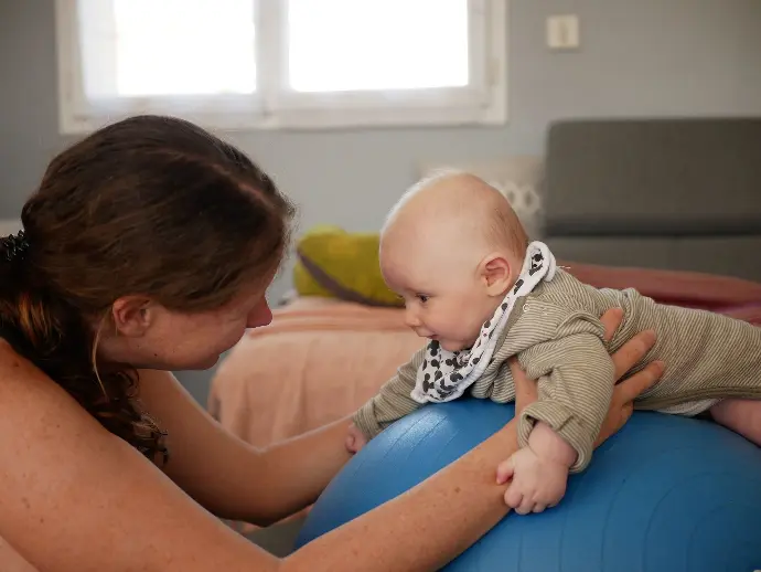 bébé à plat ventre sur un gros ballon face à la thérapeute