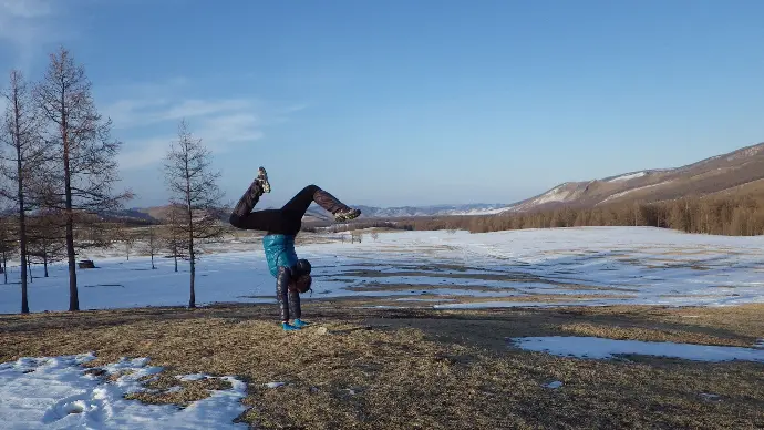 femme en équilibre sur ses main devant un paysage d'hiver